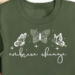 Embrace Change written on a dark green sweatshirt with butterflies.