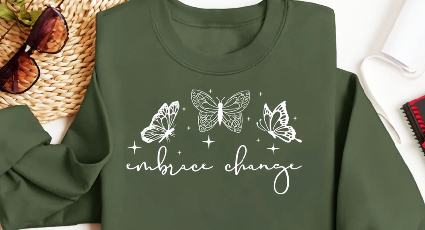 Embrace Change written on a dark green sweatshirt with butterflies.